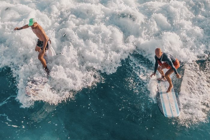 Two surfers riding the same breaking wave, seen from above