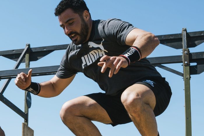 A man mid box jump at an outdoor rig under a blue sky