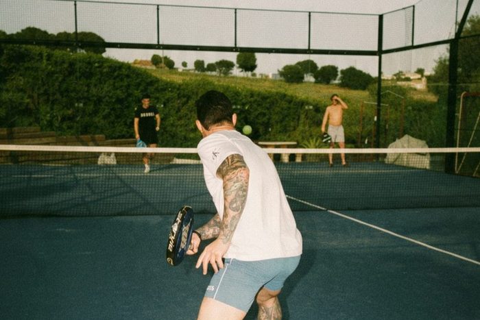 A padel game on an outdoor court, green hills behind