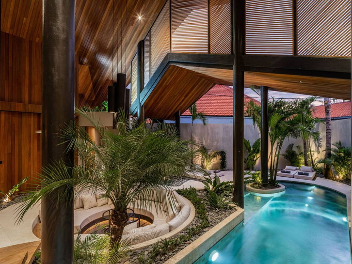 Villa pool curving around a palm island under a tropical sky