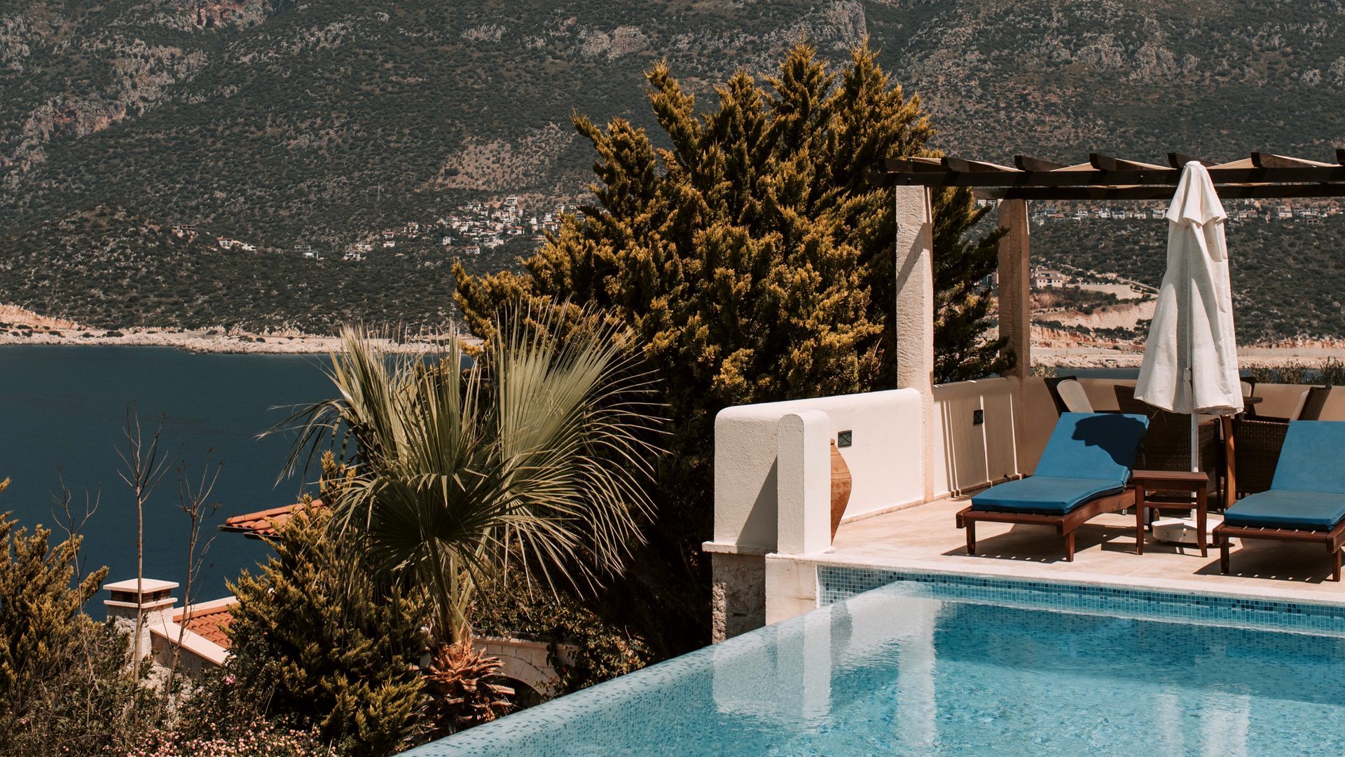 Infinity pool at the villa&rsquo;s edge, looking over the sea and coastal mountains