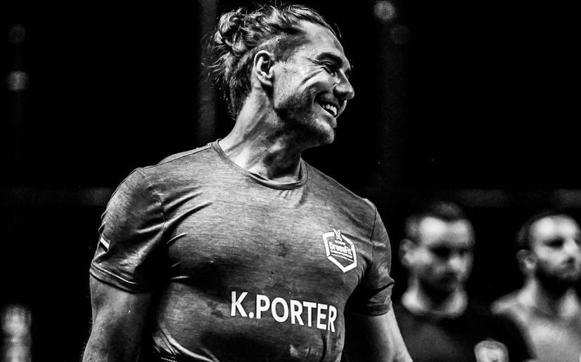 Khan Porter smiling at a CrossFit event with K.PORTER on his shirt, in black and white